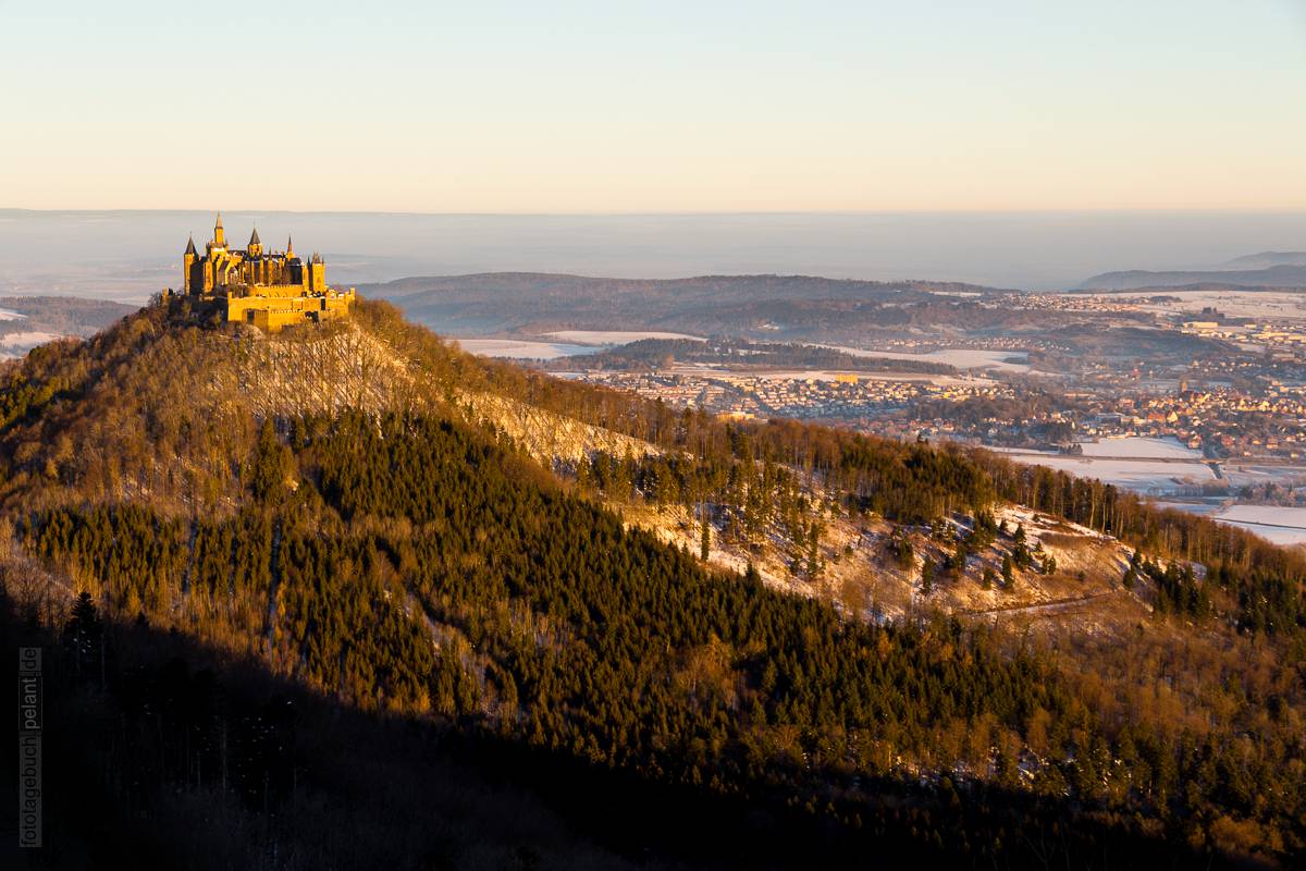 Blick auf die Burg Hohenzollern und Hechingen vom Zeller Horn bei Sonnenaufgang (im Morgenlicht) im Winter