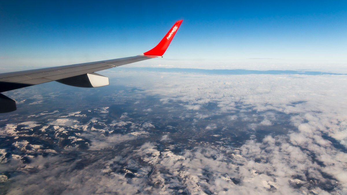 Blick aus dem Flugzeug ber der Schweiz auf aufklarende Bewlkung