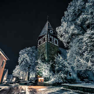 Walddorfer Kirche mit Neuschnee in einer Winternacht